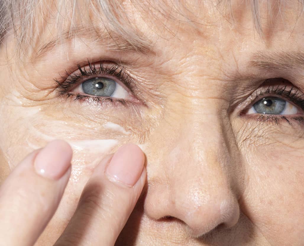 woman applying anti-aging eye cream under her eyes