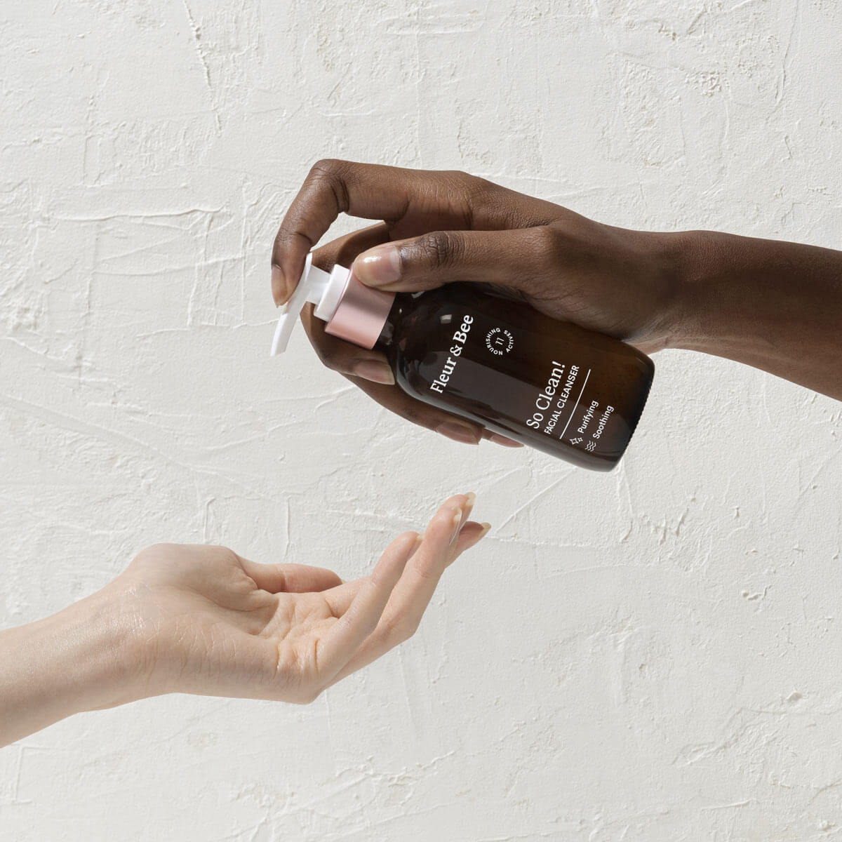 A hand holding an everyday facial cleanser and pumping a small amount into another hand