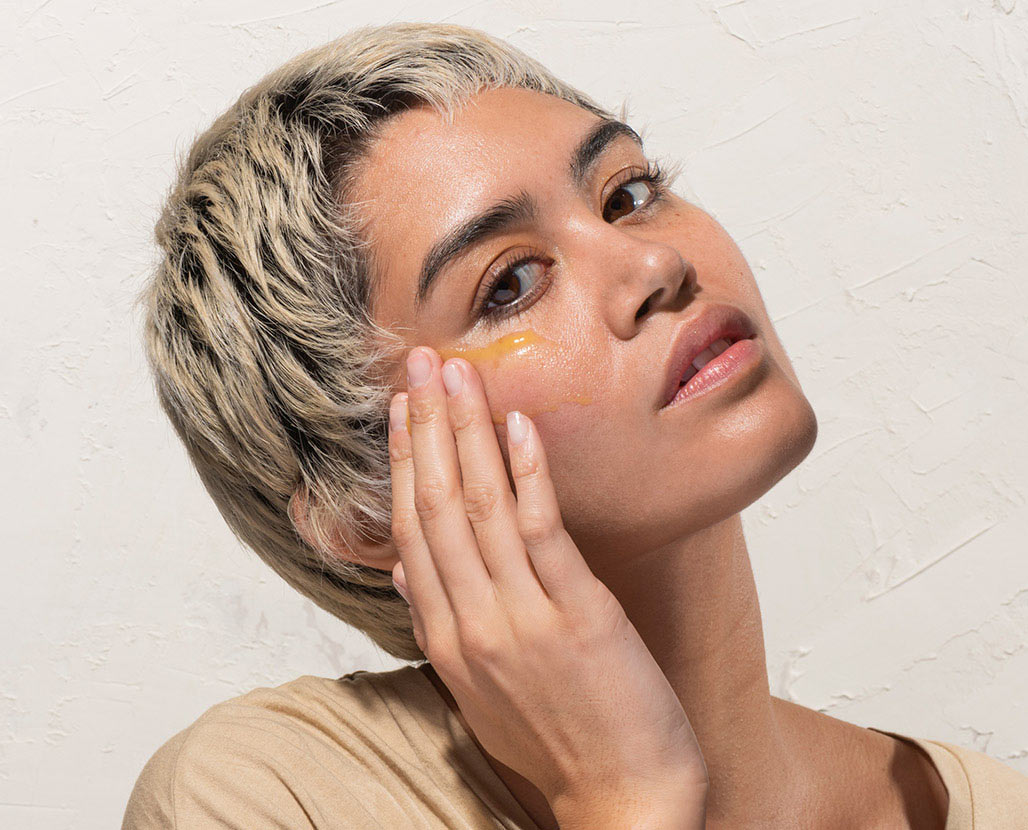 woman applying just dew it, hydrating serum to her face