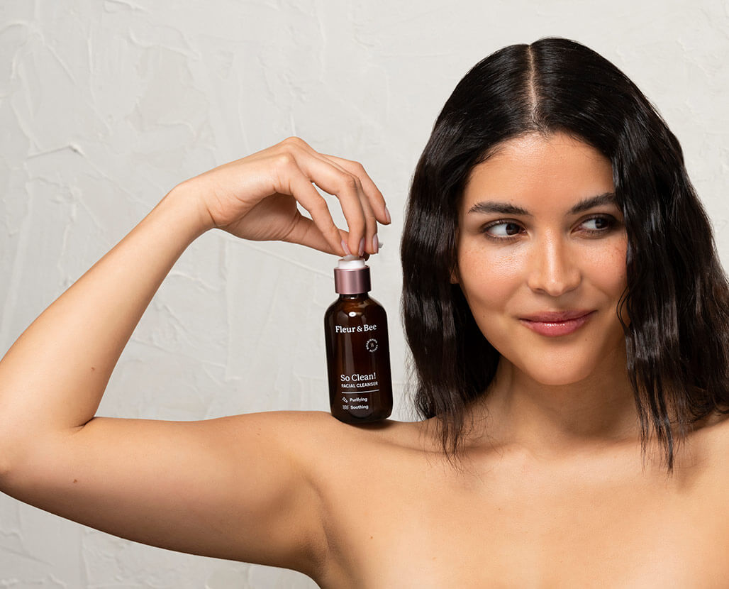 woman holding a facial cleanser on her shoulders