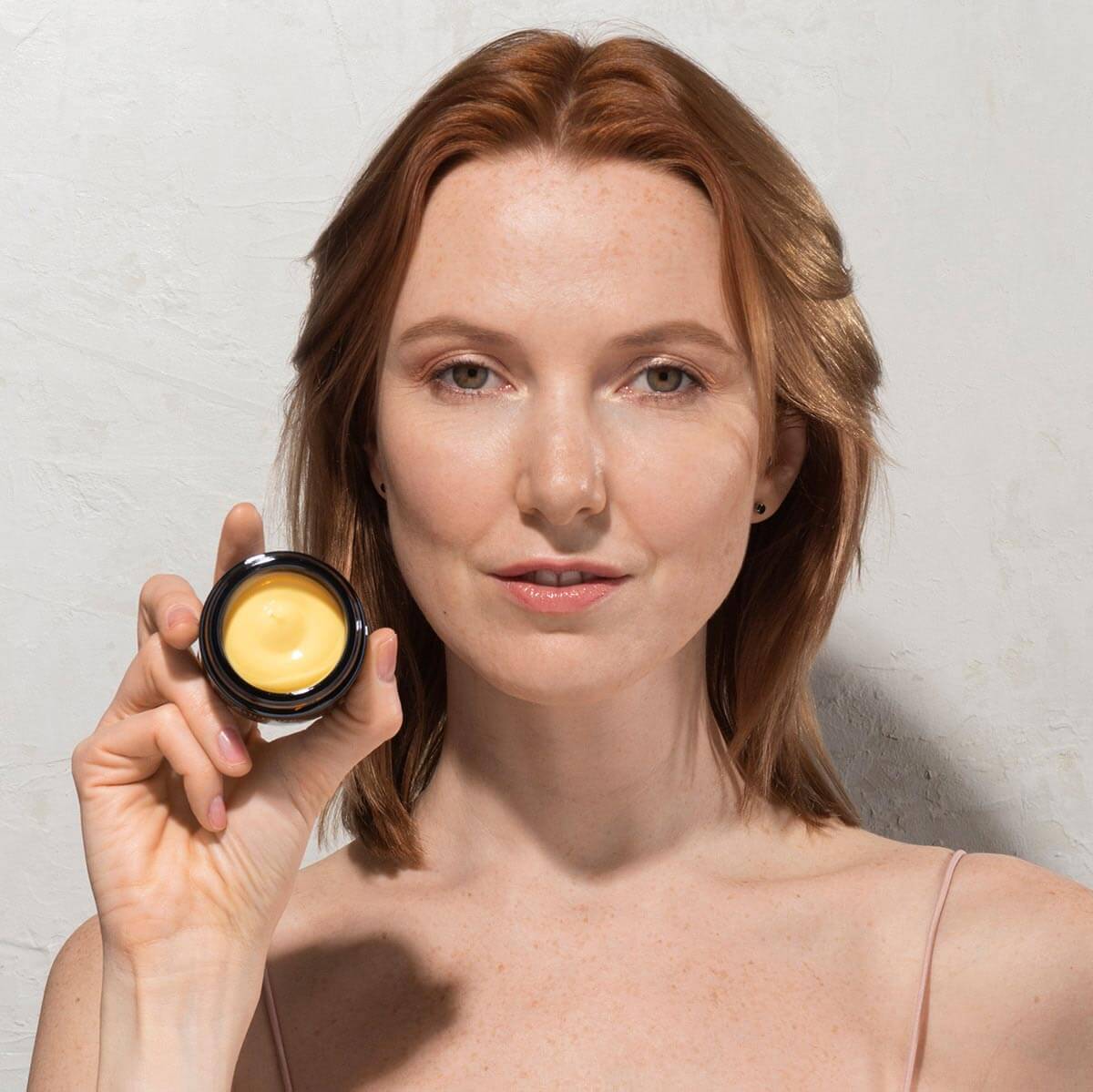 woman holding a jar of hydrating face cream