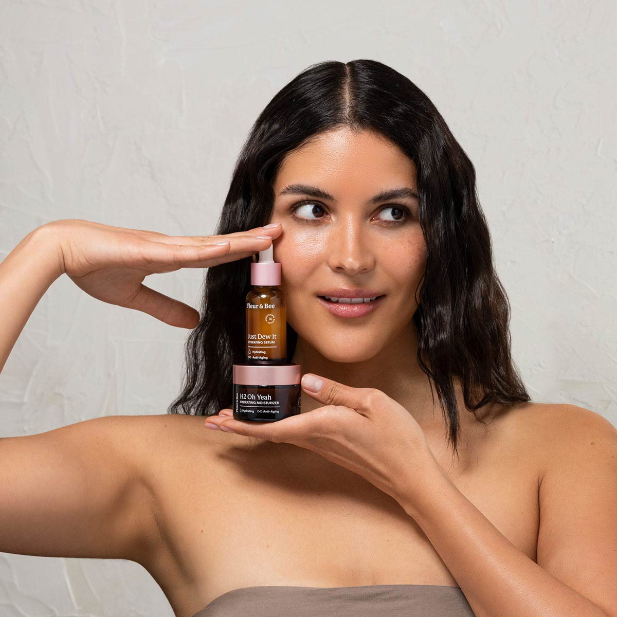 woman holding a hydrating moisturizer and hydrating serum