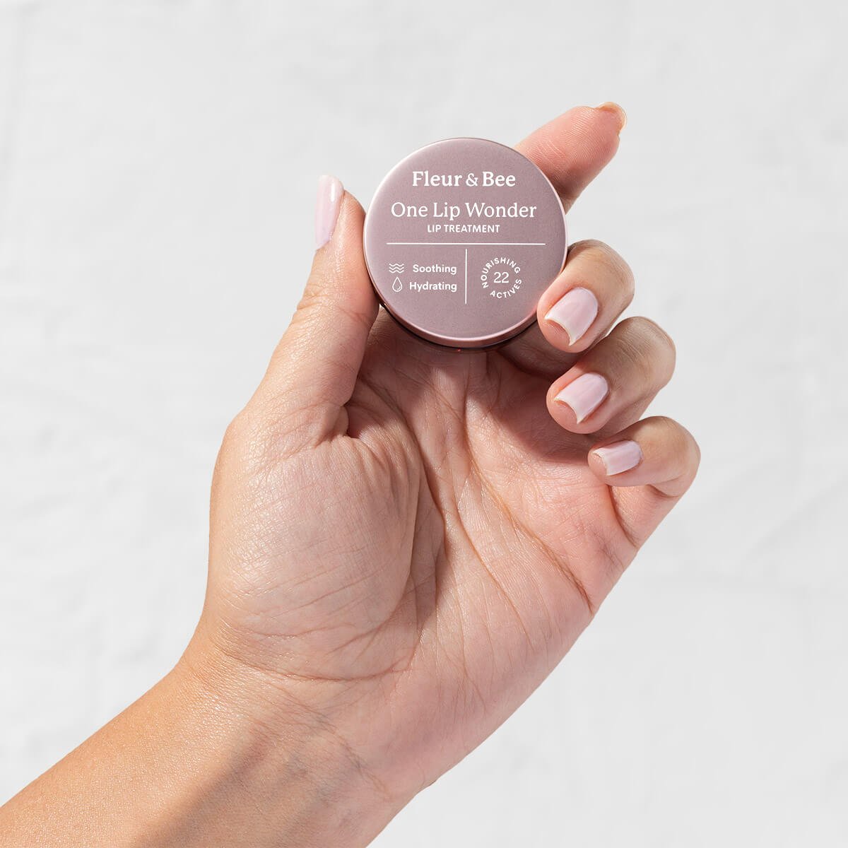 hand holding vegan lip treatment by Fleur & Bee